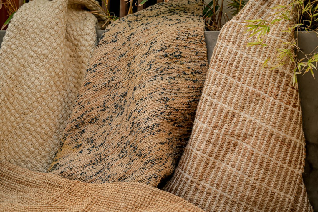 Three jute rugs draped side by side, showing braided, speckled and open-weave textures